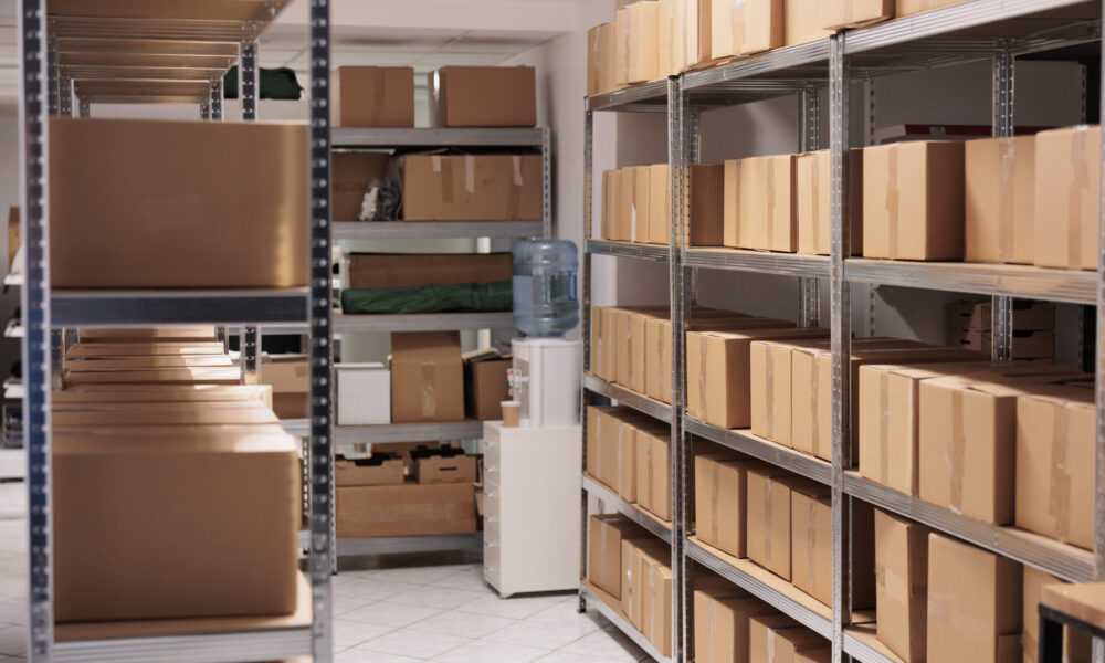 Storehouse interior with stacked cardboard boxes on tall metal racks. Goods cardboard boxes on shelves ready for transportration in industrial warehouse building with nobody inside